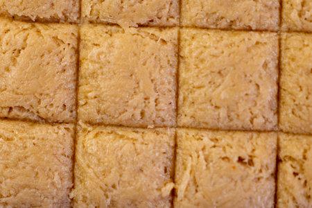 Close-up of delicious, golden chikki squares, ready to be enjoyed.  A perfect texture for backgrounds or food blogs.の写真素材