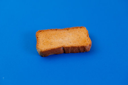 Crispy, golden rusk on vibrant blue backdrop. Perfect for food blogs, breakfast themes, or simple snack visuals.の写真素材