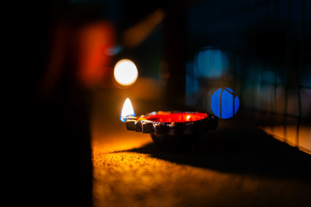 A traditional diya lit during Diwali, casting a warm glow in the darkness. Celebrates the festival...
