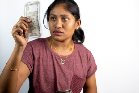 Young Indian woman inspects a 500 rupee note, exploring its details.の写真素材