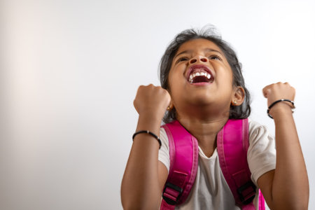 Excited young girl with backpack celebrates school success. Perfect for education, back to school, or achievement themes.の写真素材