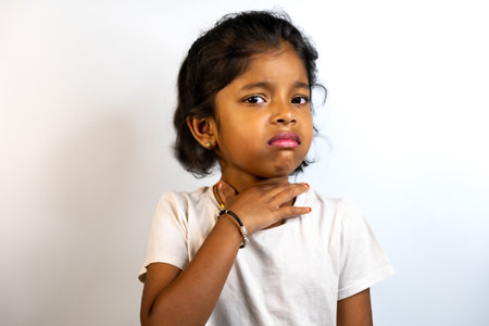 Young girl with sore throat touching her neck. Health, illness, and childhood concept.