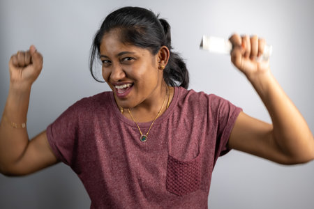 Young woman celebrates with a winning lottery ticket, expressing pure joy and excitement.