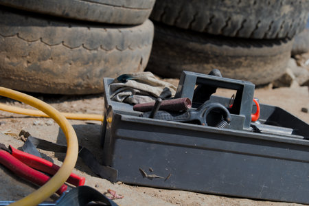 Worn toolbox with tools sits by discarded tires on a dusty construction site. Ready for the next job.の写真素材