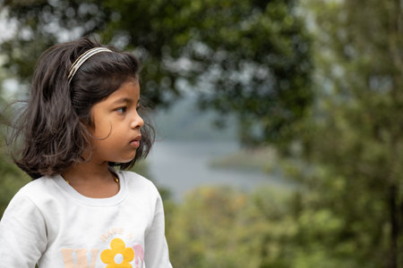 Portrait of a cute little girl in the park with nature background