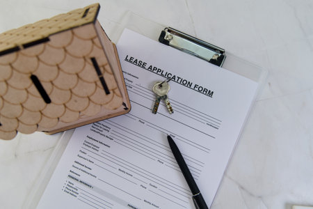 A lease application form is displayed alongside keys and a decorative house model, symbolizing a new rental opportunity.の写真素材
