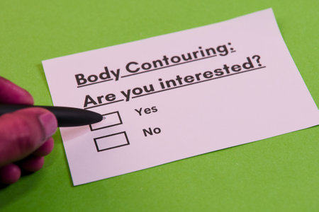 A person marks interest on a survey card about body contouring using a black pen on a vibrant green surface.の写真素材