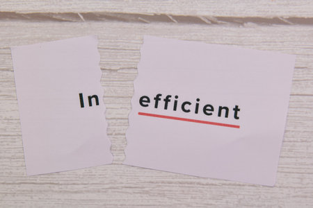 Torn pieces of paper show the word inefficient with a red underline on a white wooden background.の写真素材