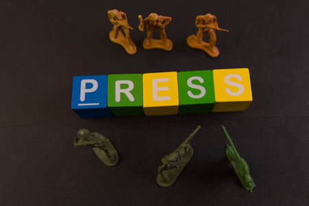 Colorful blocks spell press with miniature soldiers representing news and media themes on a dark background.の写真素材