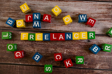 Colorful blocks spell freelancer on rustic wood, showcasing creativity in a playful scene.の写真素材