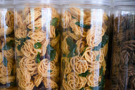 Assortment of vibrant noodles in clear jars at a local market, showcasing various shapes and colors...