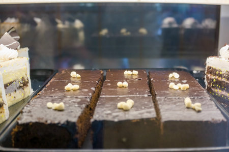 Chocolate cake slices with frosting displayed in a bakery showcase, highlighting tempting desserts on offer.の写真素材
