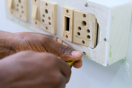 Hands using tools to fix electrical sockets at home, showcasing DIY skills and home improvement.