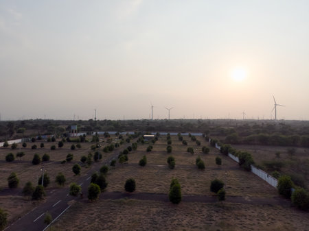 Expansive rural landscape with wind turbines at sunset, showcasing open fields and trees.の写真素材
