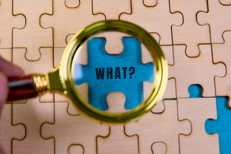 Magnifying glass highlights a puzzle piece with the word WHAT printed in bold, revealing the...