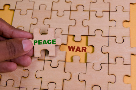 A puzzle piece labeled peace aims to fit into a war-themed puzzle, symbolizing hope.