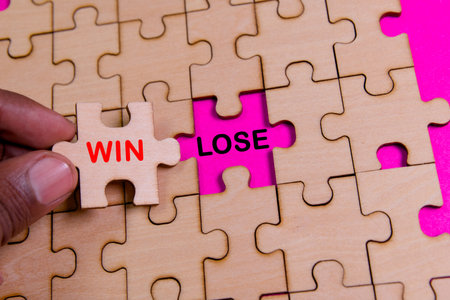A hand places a wooden puzzle piece labeled win into a puzzle with lose highlighted, symbolizing...