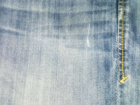 Blue jeans fabric with a seam and a string of threadsの写真素材