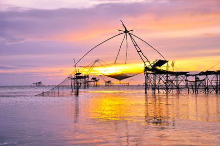 Silhouette fishing gear. Bamboo and big net in lake, Thailand.の写真素材