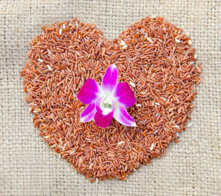 raw brown rice of heart shape on sack の写真素材