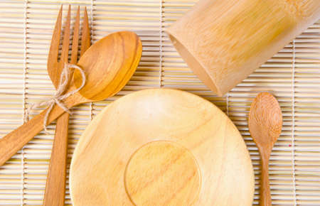 Handcrafted wooden kitchen utensils on bamboo weave backgroundの写真素材