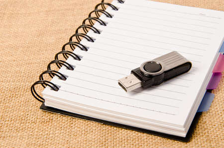 open diary ring binder and Flash drive on sack background.の写真素材