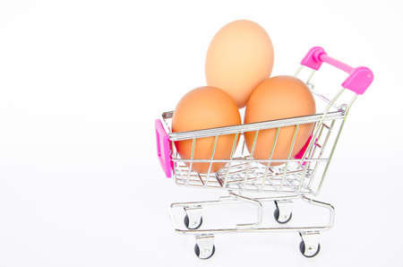 Eggs in the shopping cart on white background. Brown eggs in the basketの写真素材