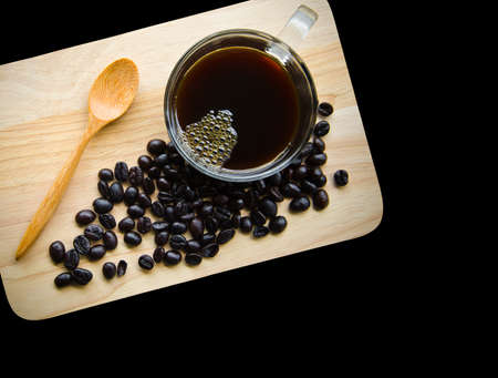 Black coffee in glass cup and seed coffee on wooden background.の写真素材