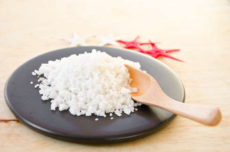 Healthy sea salt in bowl on wooden background.