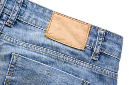 Blank leather jeans label sewed on a blue jeans. on white background.