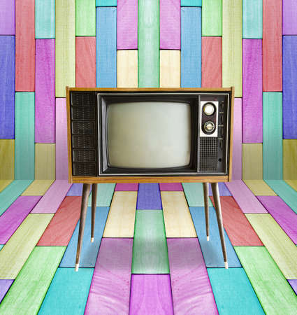 Old vintage TV television on colorful wooden wall background.の写真素材