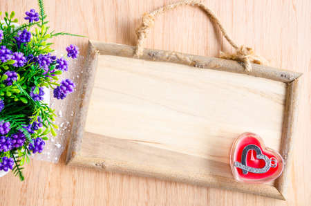 wooden photo frame and pendant in the shape of heart on wooden background.の写真素材