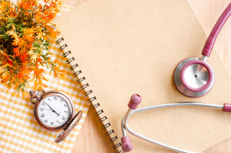 Stethoscope on Diary and vintage clock with flower on wooden background.の写真素材