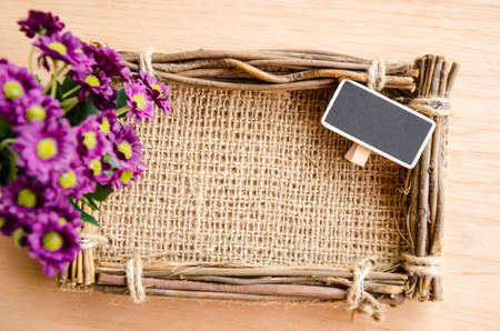 Sack photo frame, blank tag and violet fower on wooden background.の写真素材