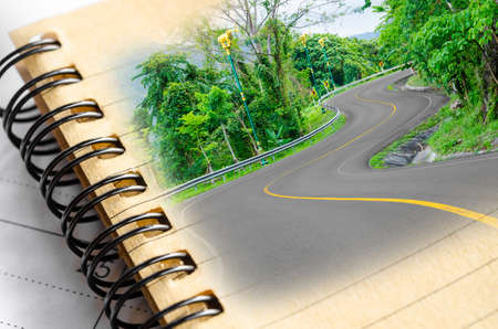S-Curved road to mountain with blank diary. Time and memory with journey concept.の写真素材