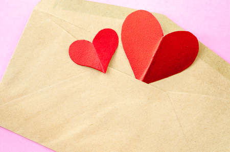 red heart paper in brown envelopes on pink background.の写真素材