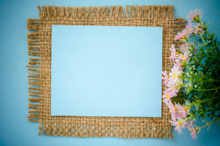 Blue paper blank card on sack with pink flower for your text.の写真素材