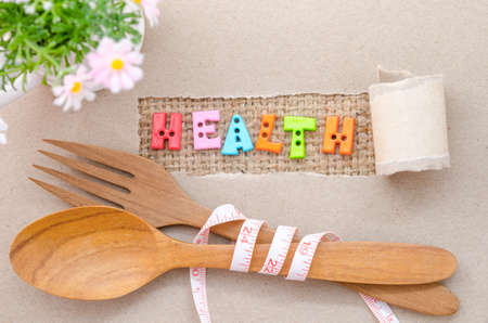 Health word and wooden spoon with Measure tape on brown paper background.の写真素材