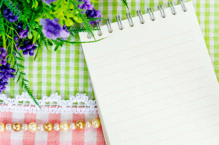 Open diary and violet flower on beautiful background from top view