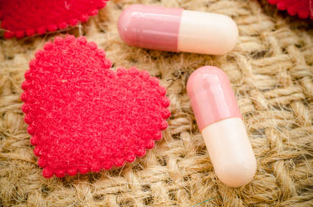 Capsule pill and red heart on sack background.の写真素材