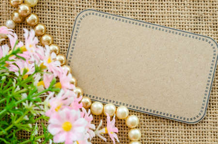 Blank brown tag paper with flower on sack background for your text.の写真素材