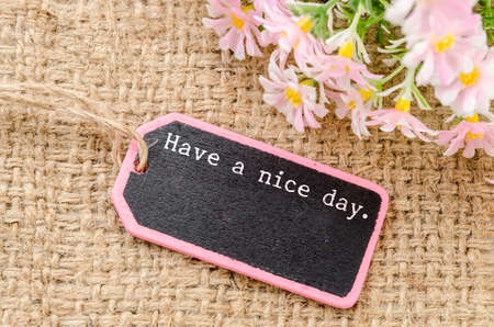 Have a nice day on wooden tag and copy space for your text with flower on sack background.の写真素材