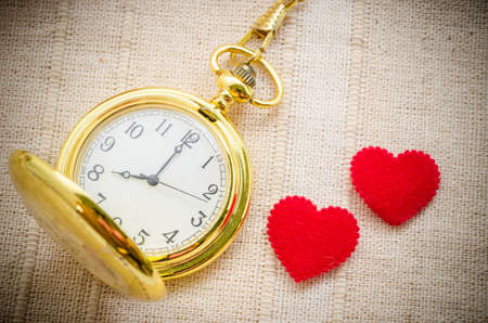 Gold pocket watch and red heart on sack background. Love concept.の写真素材