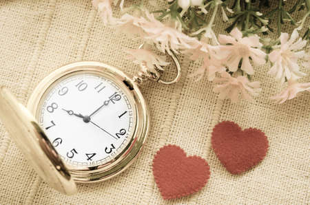 Gold pocket watch and red heart with flower on sack background. Love concept.の写真素材