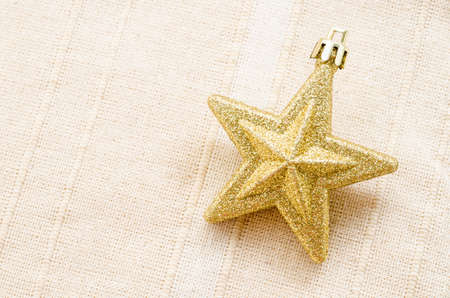 Gold five pointed star christmas decoration on fabric background.の写真素材