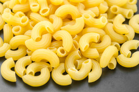 Elbow macaroni noodles on black dish background.の写真素材