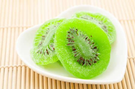 Dried kiwi in white bowl heart shape on mat background.の写真素材