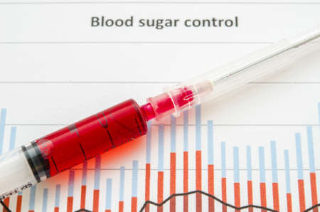 Sample blood for screening diabetic test in blood tube on blood sugar control chart.の写真素材