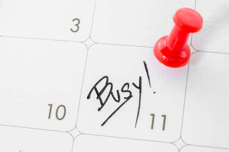 The words Busy written on a white calendar to remind you an important appointment.の写真素材