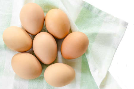 Fresh eggs in fabric on white background.